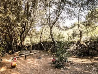 a park with a bench and trees and a stone wall at Mobil Home 3 Chambres avec Terrasse - Pour 6 Personnes - API-1-52-1659 in Sartène