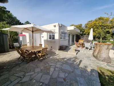 a patio with a wooden table and an umbrella at CORSE bord de plage SANT AMBROGGIO