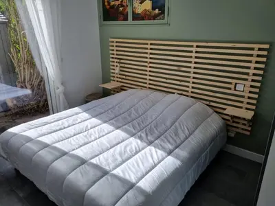 a bedroom with a large bed with a wooden headboard at CORSE bord de plage SANT AMBROGGIO