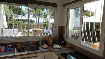 a kitchen with two windows and a sink and a patio at CORSE bord de plage SANT AMBROGGIO