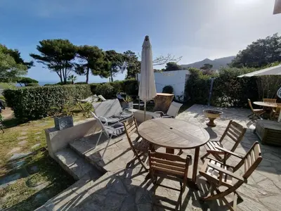 a patio with a table and chairs and an umbrella at CORSE bord de plage SANT AMBROGGIO