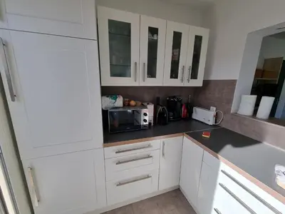 a kitchen with white cabinets and a microwave at CORSE bord de plage SANT AMBROGGIO