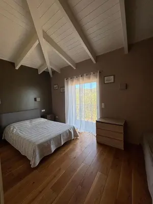 a bedroom with a bed and a large window at VILLA Cala D'orzu in Coti-Chiavari