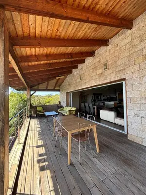 a wooden patio with a table and chairs on a deck at VILLA Cala D'orzu in Coti-Chiavari
