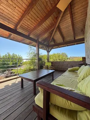 a bed and a table on a wooden deck at VILLA Cala D'orzu in Coti-Chiavari