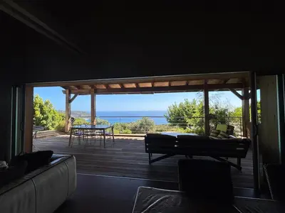 a screened in porch with a view of the ocean at VILLA Cala D'orzu in Coti-Chiavari