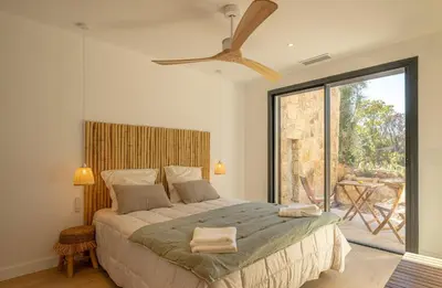 a bedroom with a large bed and a large window at Villa CASATANGO in Zonza