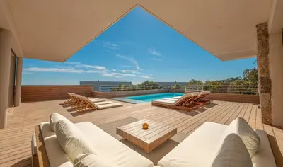a patio with white furniture and a swimming pool at Villa CASATANGO in Zonza
