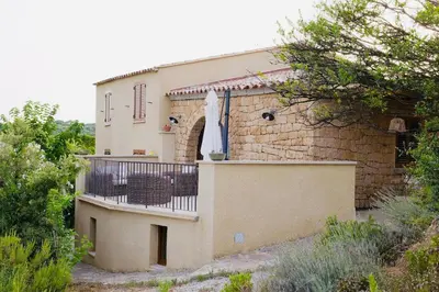 a building with a balcony with a umbrella on it at Charmante villa dans un petit coin de Paradis in Propriano