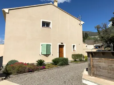 a house with a green window and a gravel driveway at A Murella - maison de vacances à Oletta en Corse in Oletta