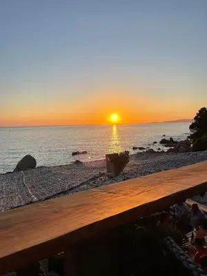 a sunset on the beach with a wooden bench at u limone in Porticcio