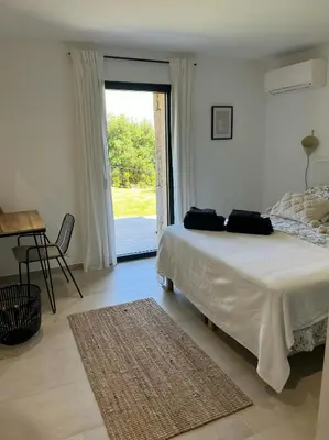 a bedroom with a bed and a table and a window at Granite Villa Between Porto-Vecchio And Bonifacio in Figari