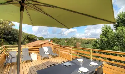a deck with a table and chairs and an umbrella at Appartement avec grande terrasse in Viggianello