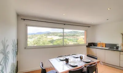 a dining room with a table and a large window at Appartement avec grande terrasse in Viggianello