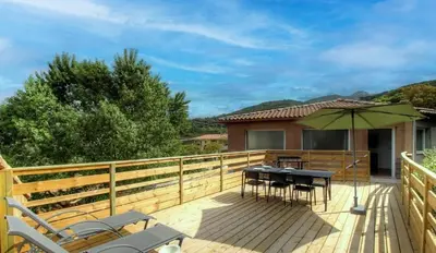 a wooden deck with a table and an umbrella at Appartement avec grande terrasse in Viggianello