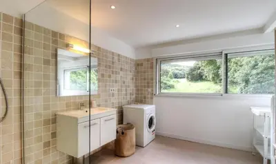 a bathroom with a sink and a washing machine at Appartement avec grande terrasse in Viggianello