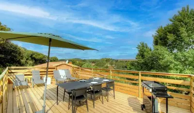 a deck with a table and an umbrella and a grill at Appartement avec grande terrasse in Viggianello