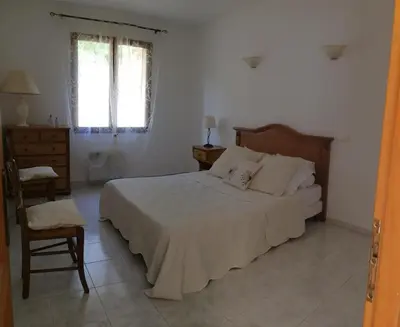 a bedroom with a bed and a chair and a window at Maison avec piscine sans voisinage à 4km de la mer in Canale-di-Verde
