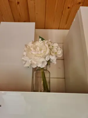 a vase filled with white flowers sitting on a shelf at Casa Di Legnu -T2 - Calme et bien situé in Appietto