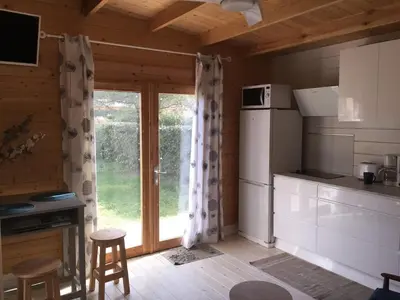 a kitchen with a refrigerator and a table and chairs at Casa Di Legnu -T2 - Calme et bien situé in Appietto
