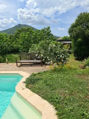 a bench sitting on a deck next to a swimming pool at Casa Di Legnu -T2 - Calme et bien situé in Appietto