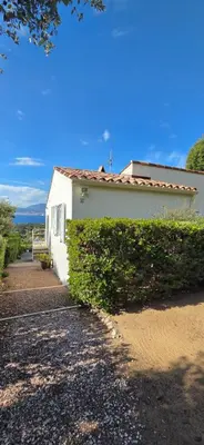 a white building with a green hedge next to it at Maison vue mer Porticcio in Porticcio