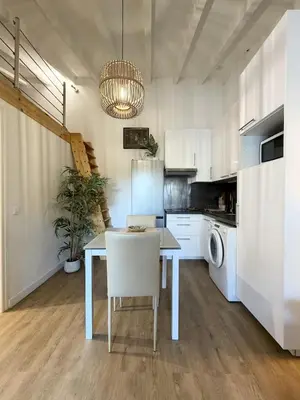 a kitchen with white cabinets and a table with a chair at Charmant studio au centre de Porticcio in Grosseto-Prugna