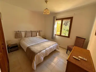 a bedroom with a bed and a table and a window at Charmante Villa Privée avec Piscine in Porto-Vecchio