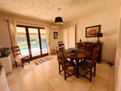a dining room with a wooden table and chairs at Charmante Villa Privée avec Piscine in Porto-Vecchio