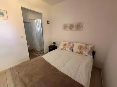a small bedroom with a bed with white sheets and pillows at Charmante Villa Privée avec Piscine in Porto-Vecchio