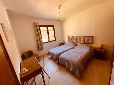a bedroom with a bed and a window and a chair at Charmante Villa Privée avec Piscine in Porto-Vecchio