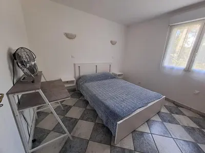 a bedroom with a bed and a chair and a window at Villa Mare E Muntagna in Porto-Vecchio