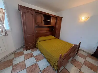 a bedroom with a bed and a wooden cabinet at Villa Mare E Muntagna in Porto-Vecchio