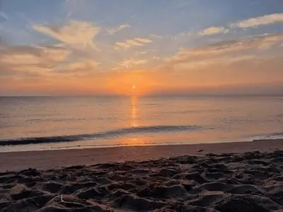 a sunset on a beach with the sun setting over the ocean at Petit havre de paix au bord de la mer in Linguizzetta