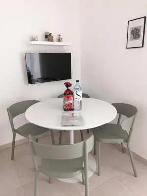 a white table and chairs with a bottle on it at Petit havre de paix au bord de la mer in Linguizzetta