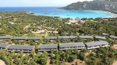 a large swimming pool with chairs and a wooden deck at Santa Giulia, Résidence Cala Sultana Numero 40 in Porto-Vecchio