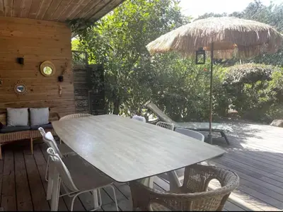 a table with chairs and an umbrella on a deck at Santa Giulia, Résidence Cala Sultana Numero 40 in Porto-Vecchio