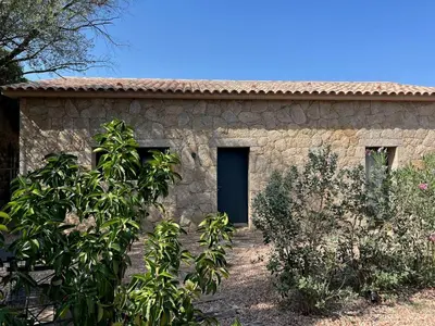 a stone house with a black door and trees at Stone House Between Porto-Vecchio And Bonifacio in Figari