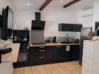 a kitchen with black cabinets and a wooden counter top at Studio maisonnette au bord de belle plage d'Agosta in Albitreccia