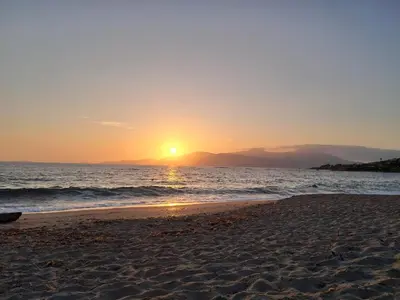 a beach with the sun setting in the distance at Studio maisonnette au bord de belle plage d'Agosta in Albitreccia