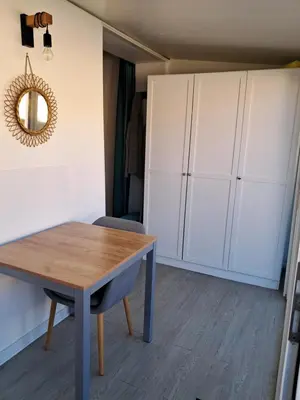 a dining room with a table and white cabinets at Studio maisonnette au bord de belle plage d'Agosta in Albitreccia