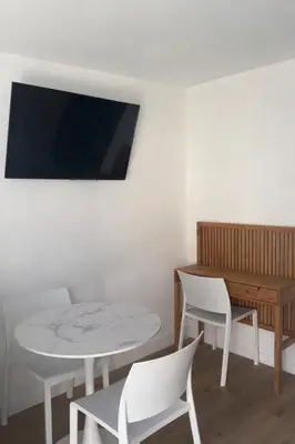 a room with a table and chairs and a television at Studio climatisé avec terrasse privative in Corte