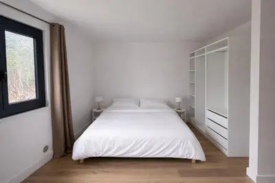 a white bedroom with a bed and a window at Studio climatisé avec terrasse privative in Corte