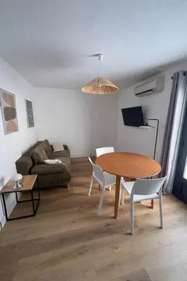 a living room with a table and a couch at Appartement T2 climatisé avec terrasse privative in Corte
