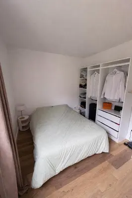 a bedroom with a white bed and open closet at Appartement T2 climatisé avec terrasse privative in Corte