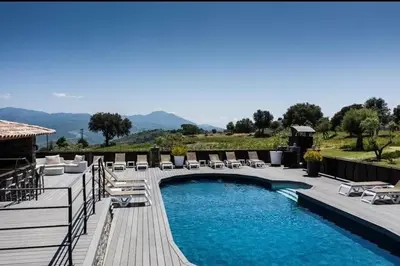 a swimming pool with lounge chairs on a wooden deck at Appartement T2 climatisé avec terrasse privative in Corte
