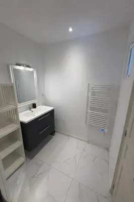 a kitchen with a table and chairs and a black refrigerator at Appartement T2 climatisé avec terrasse privative in Corte