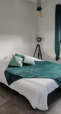 a bed with green and white sheets and pillows at Villa 6 personnes Corse du Sud in Afa