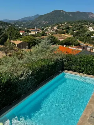 a blue swimming pool with mountains in the background at Villa 6 personnes Corse du Sud in Afa
