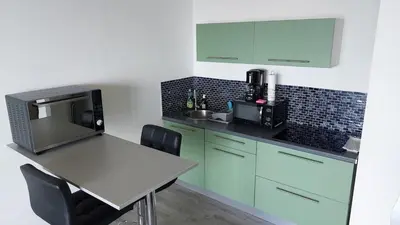 a kitchen with green cabinets and a table with a microwave at Studio AJACCIO Sanguinaires in Ajaccio